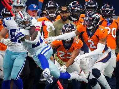 Dallas Cowboys running back Ezekiel Elliott (21) is knocked out of bounds by Denver Broncos cornerback Pat Surtain II (2) and cornerback Kyle Fuller (23) during the first half of an NFL football game at AT&T Stadium on Sunday, Nov. 7, 2021, in Arlington.