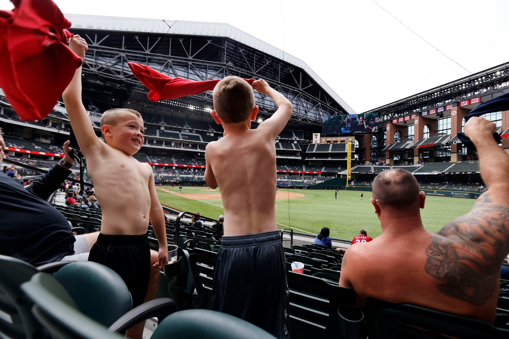 Young Texas Rangers fans try to rally their team in the ninth inning by taking off their shirts and twirling them in the air at Globe Life Field in Arlington, Texas. The Rangers were playing an exhibition game against the Milwaukee Brewers, Tuesday, March 30, 2021. (Tom Fox/The Dallas Morning News)