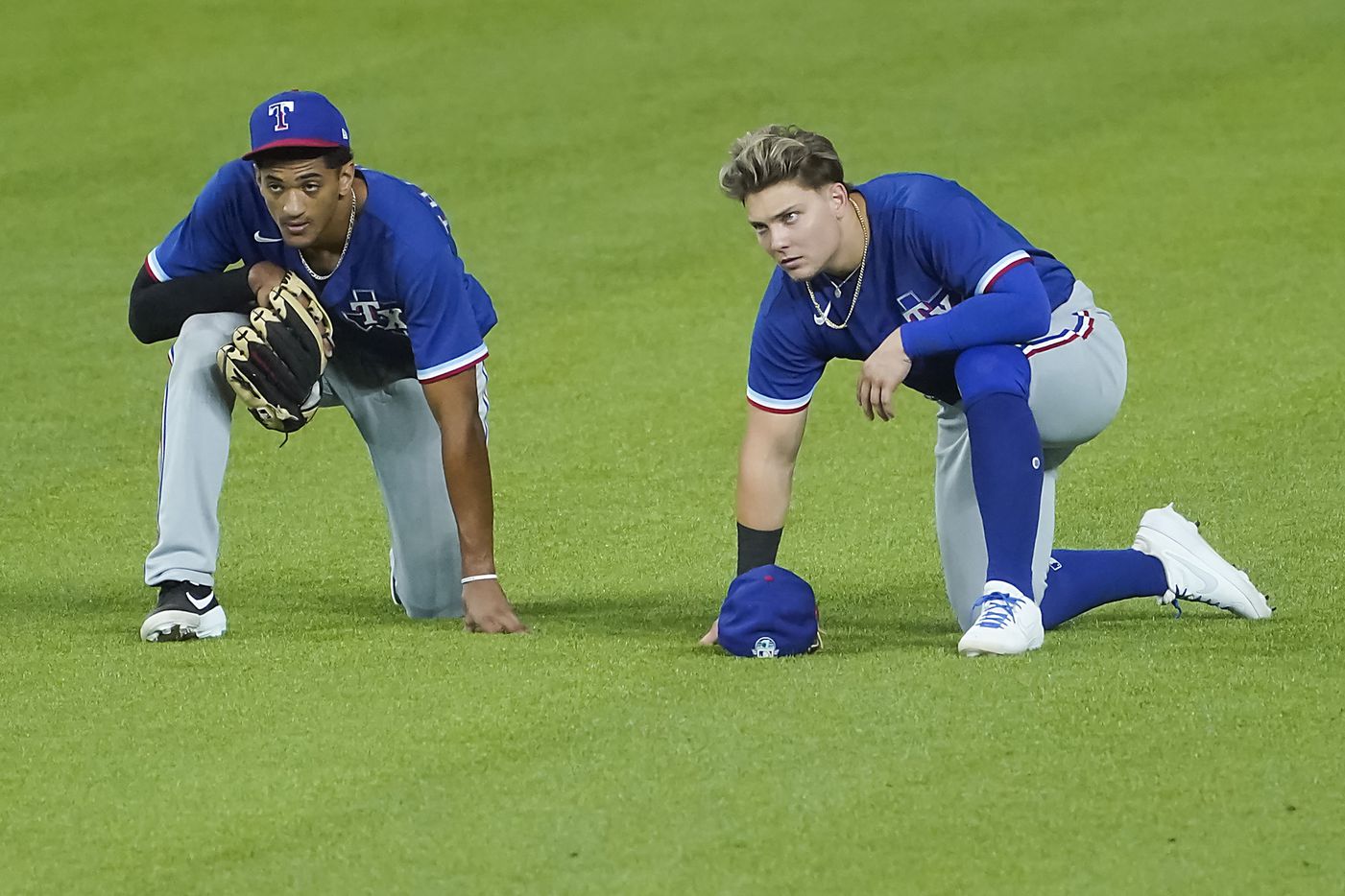 Texas Rangers outfielders Bubba Thompson (left) and Steele Walker take a knee as the watch...