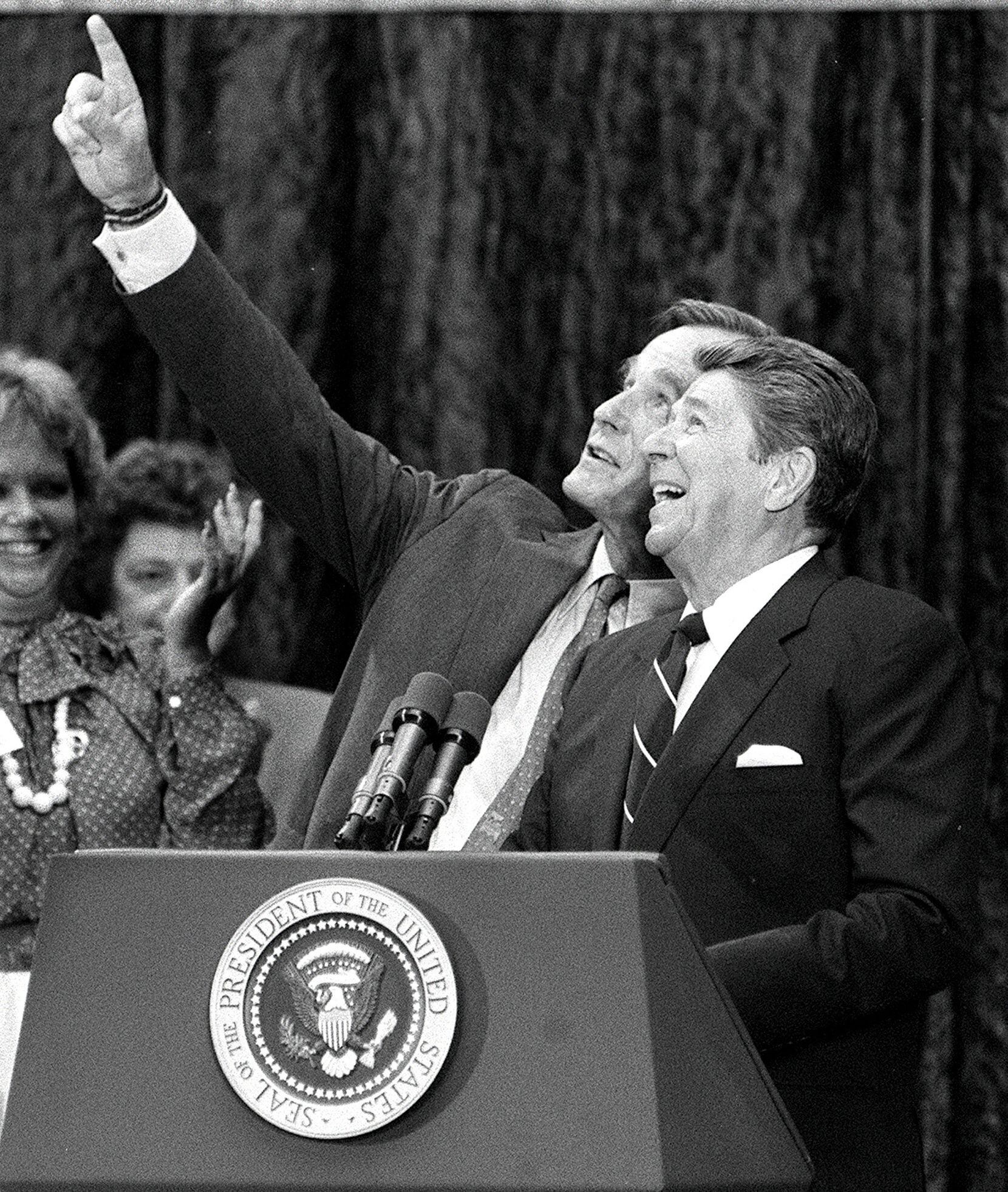 President Ronald Reagan and Vice President George H.W. Bush react to cheers and falling...