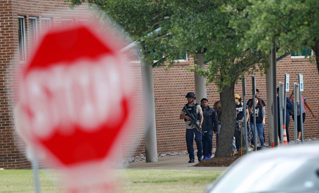 Police guide students and faculty out of a building after a shooting at North Lake College...