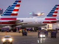 American Airlines planes are seen at the gates of Terminal C as another American flight takes off at DFW Airport on Friday, Jan. 7, 2022.