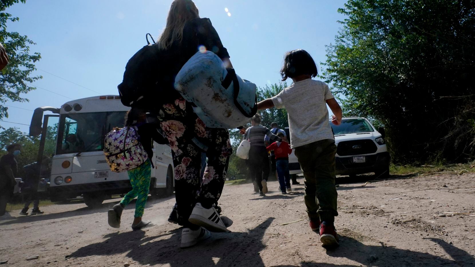 FILE - A migrant family from Venezuela walks to a Border Patrol transport vehicle after they...