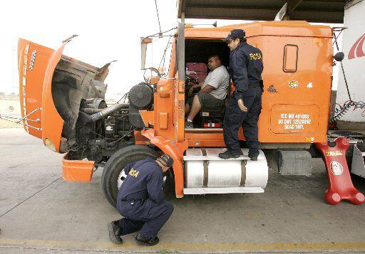 Federal Motor Carrier Safety
Administration (FMCSA) inspector Hugo Martinez, top, talks to...