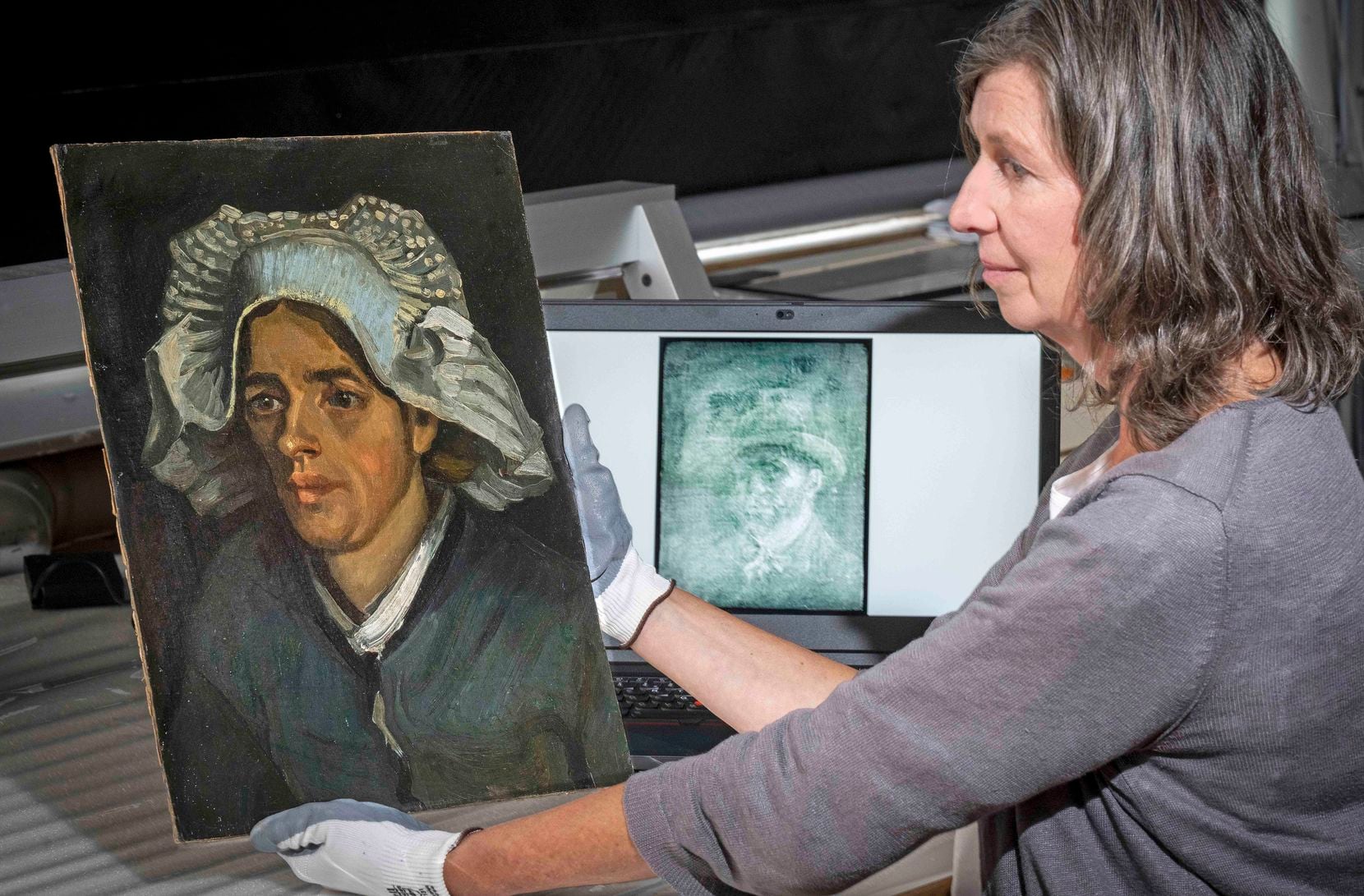 Senior Conservator Lesley Stevenson views "Head of a Peasant Woman" alongside an X-ray image...