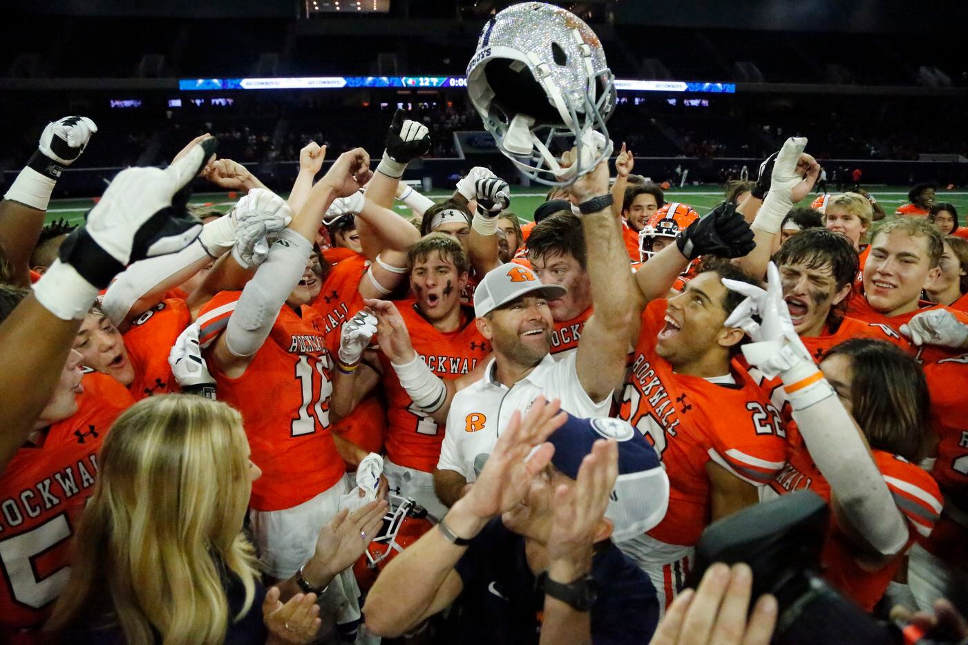 Surrounded by his team, Rockwall High School head coach Trey Brooks holds up the trophy for...