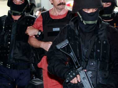 Suspected Russian arms smuggler Viktor Bout, center, is led by armed Thai police commandoes...