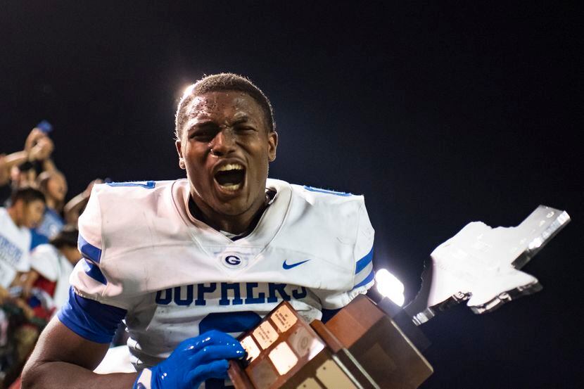 Grand Prairie senior Savion Red celebrates while holding a trophy after the conclusion of...