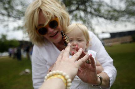Sarah Minton holds a butterfly toward her daughter Lincoln, 1, held by Sarah's mom, Amy...
