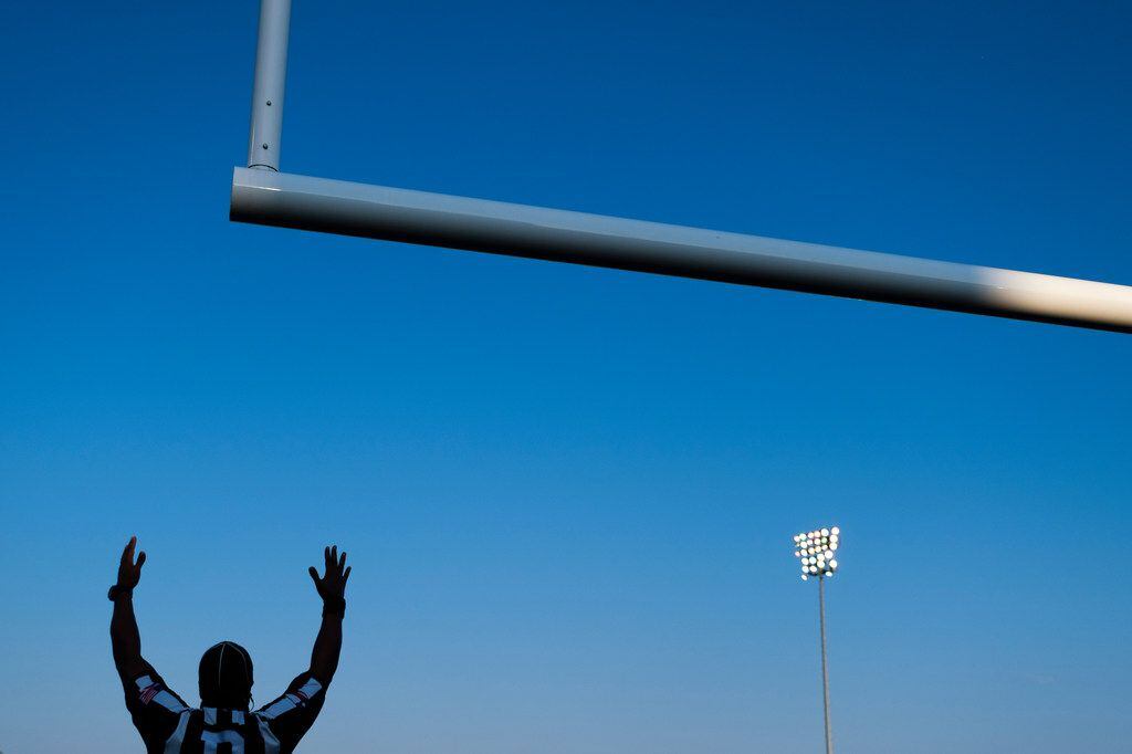 Officials signal a made extra point during the first half of a high school football game...