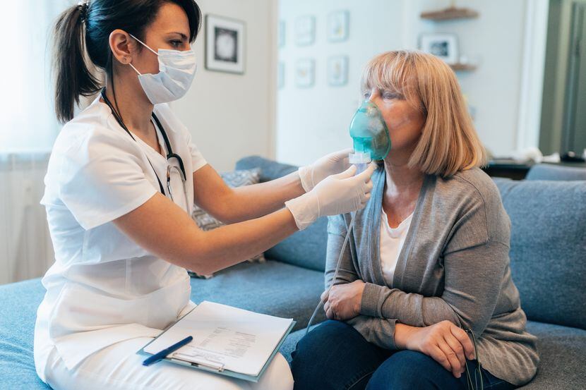 Medical doctor applies medicine inhalation treatment on senior woman by the mask of inhaler.