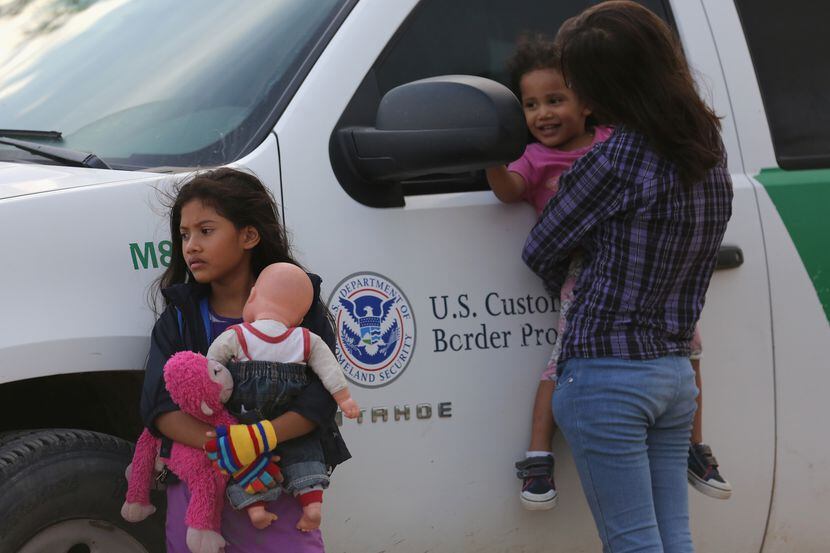 Central American immigrants await transportation to a U.S. Border Patrol processing center...