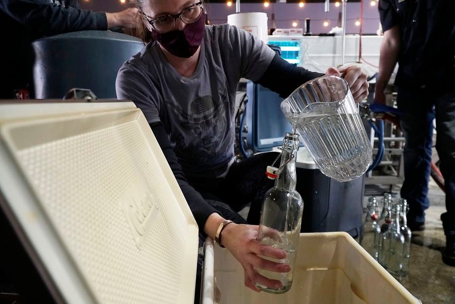 Hope Danals remplit des contenants d'eau filtrée à la brasserie Cowtown à Fort Worth.