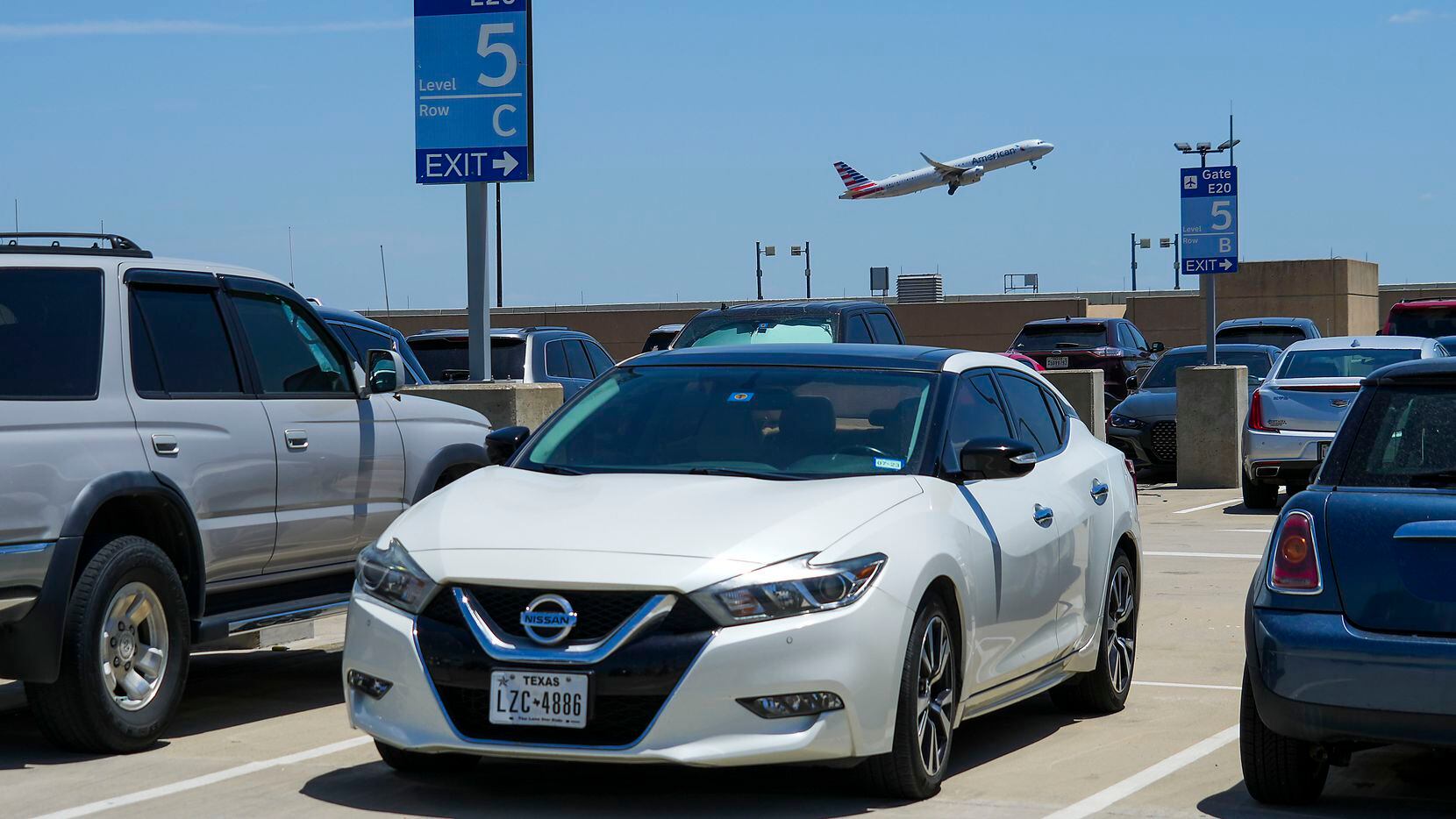 An American Airlines flight takes off over cars parked on the rooftop level of the terminal...