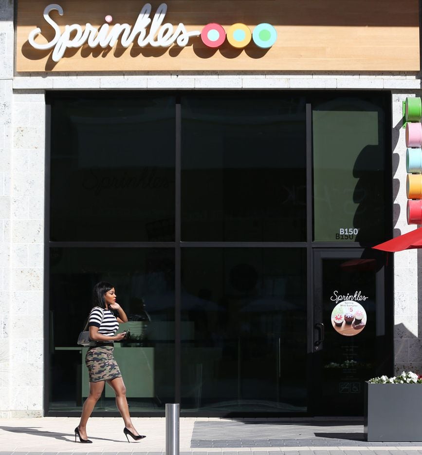 A woman walks past Sprinkles Cupcakes at Legacy West in Plano.