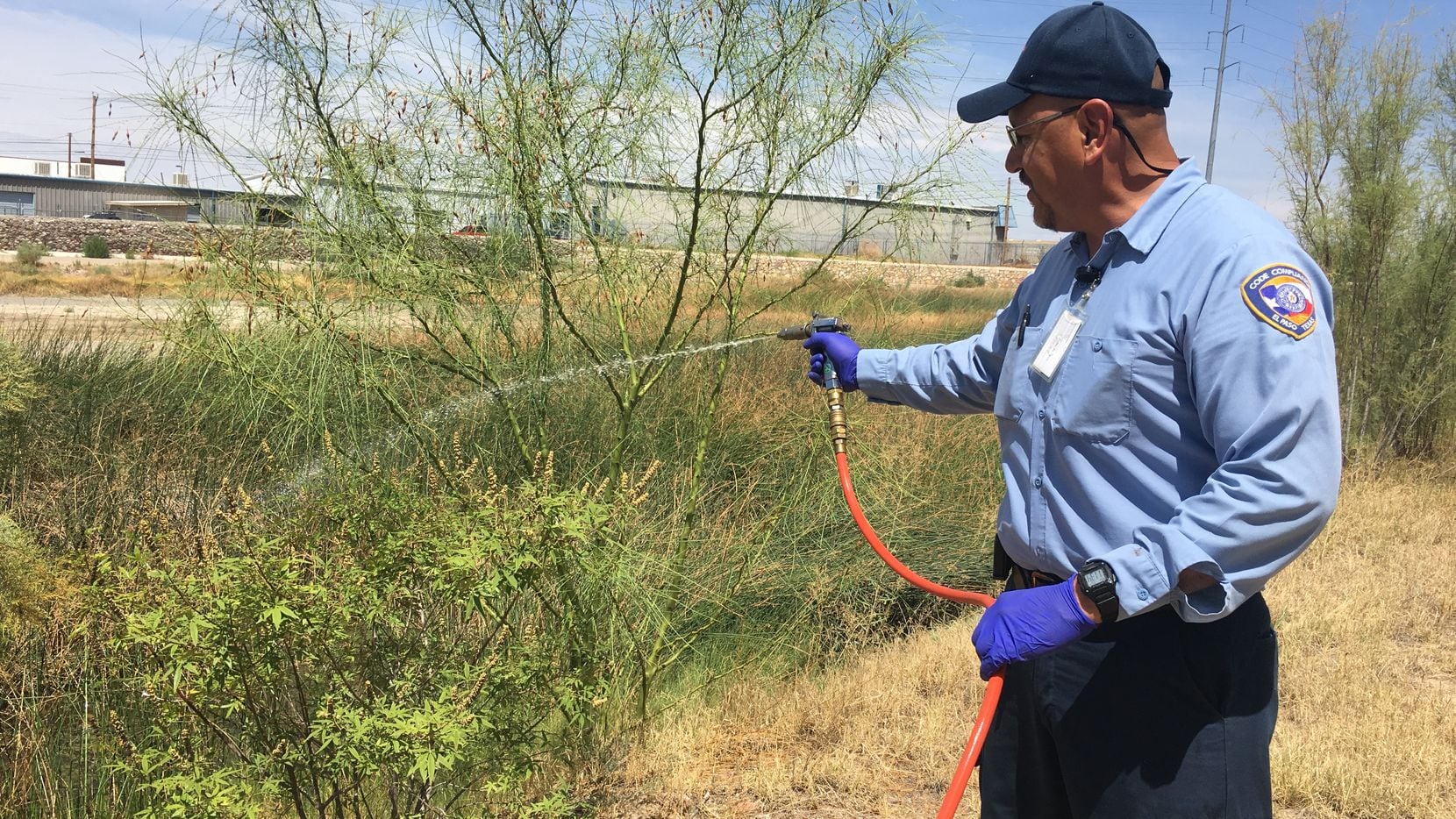 Ricardo Lino, a vector control  officer in El Paso, sprays standing water near a reservoir...