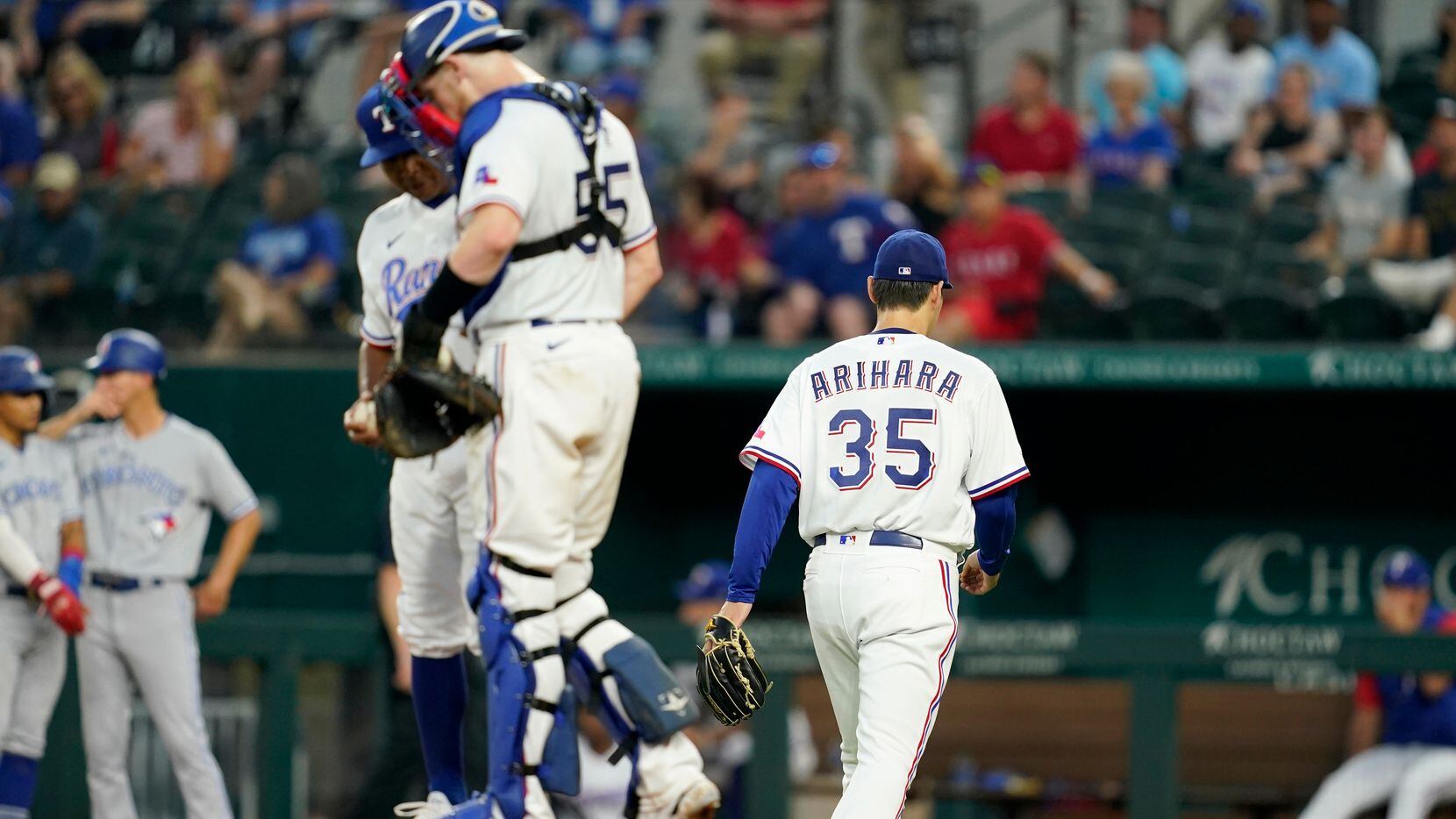 Texas Rangers starting pitcher Kohei Arihara (35) heads to the dugout after turning the ball...