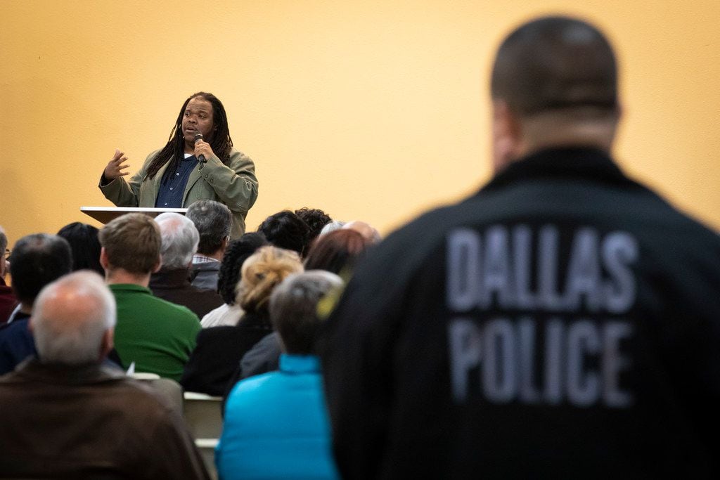 A Dallas Police officer listens as Walter "Changa" Higgins addresses a Citizens Police Review Board town hall meeting at Highland Oaks Church of Christ in January.