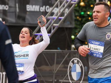 Half-marathon runners celebrate crossing the finish line at the BMW Dallas Marathon on...