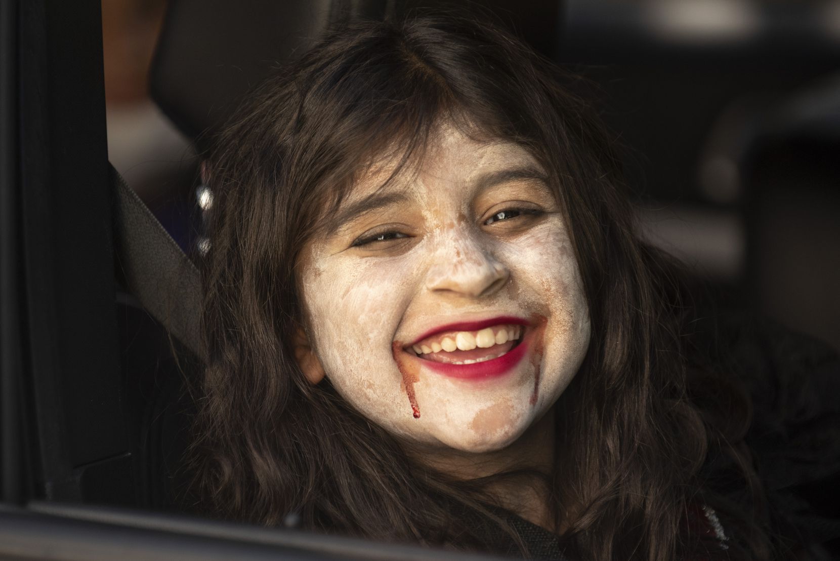 Victoria Rodriguez, 8, dressed as a young vampire, giggles as her family drives through the contactless Candy Caravan event hosted by The City of Dallas at Dallas Heritage Village, on Saturday, Oct. 31, 2020.