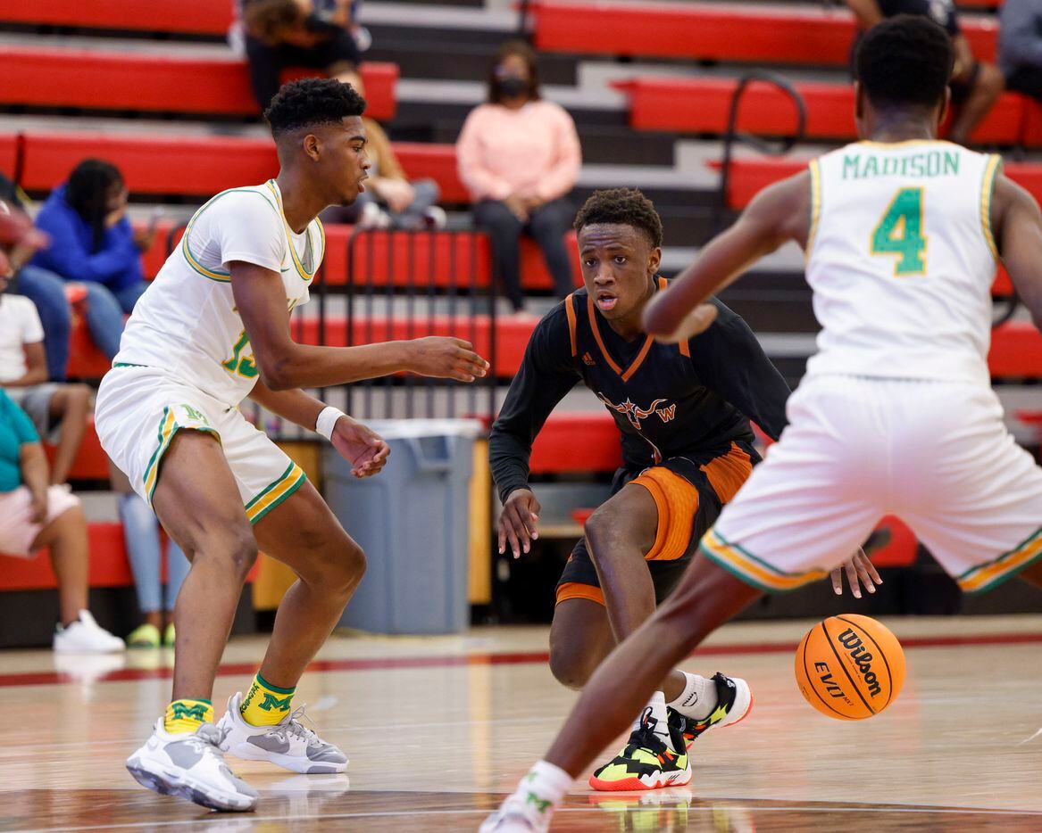 W.T. White guard Charles Fofanah (3) dribbles around Madison forward Quintin Spencer (13) and towards guard Eric Bradix (4) during the second quarter of a Dallas ISD Holiday Invitational basketball tournament game at Woodrow Wilson High School in Dallas, Tuesday, Dec. 28, 2021.