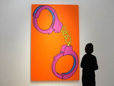 A woman walks past the work of artist Michael Craig-Martin titled Handcuffs at Christie's...