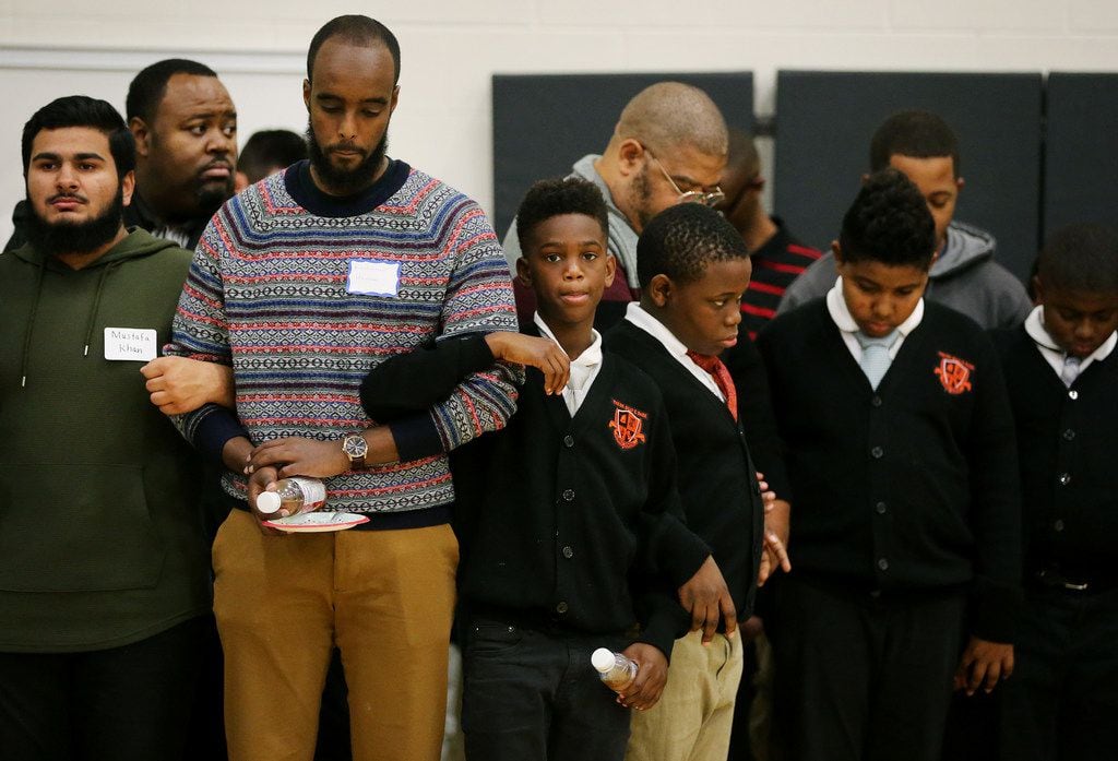 Students and mentors lock arms during a prayer at the end of the "Breakfast with Dads" event...