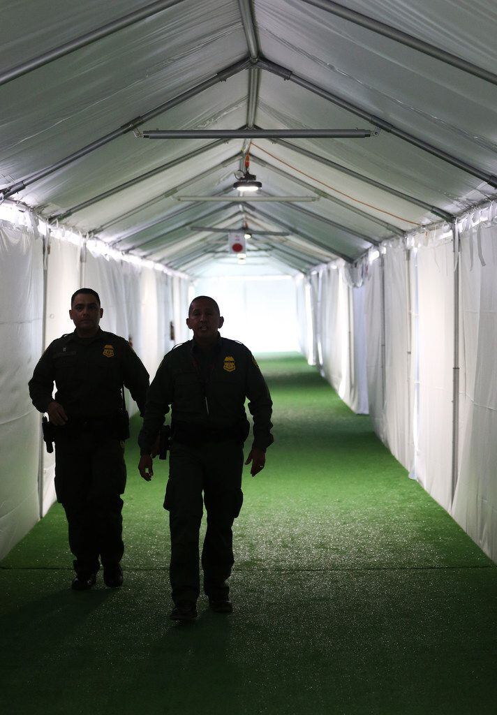 U.S. Border Patrol agents walk the hallway of a temporary holding facility near the...