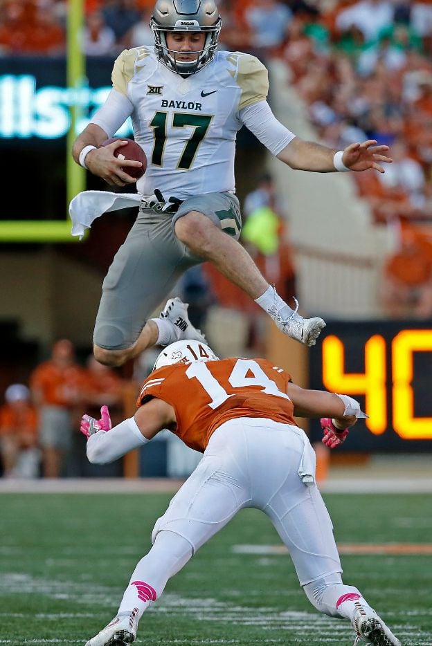 Baylor quarterback Seth Russell (17) leaps over Texas safety Dylan Haines (14) during the...
