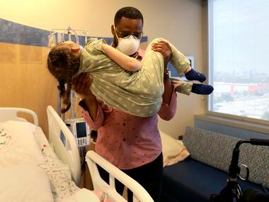 Kameron Brooks carries Charlotte Brooks, 5, from her hospital bed to her wheelchair in order...