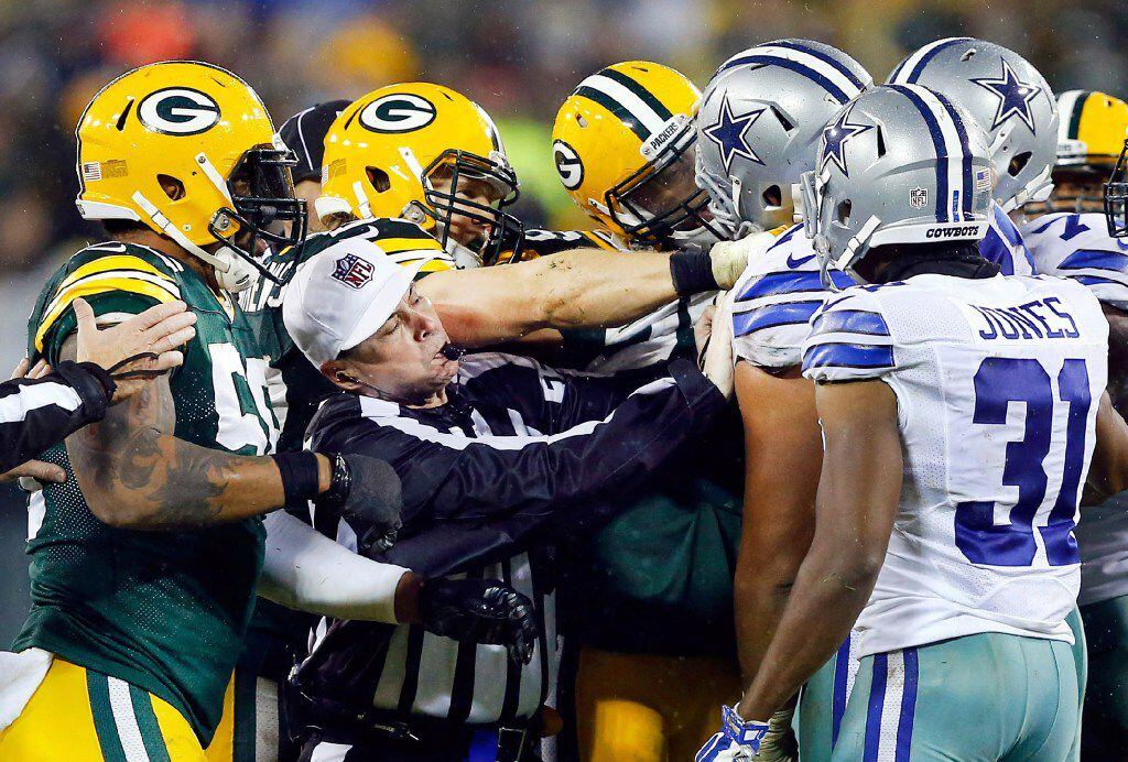 Referee Brad Allen (center) tries to break up a fight that involved Dallas Cowboys offensive...