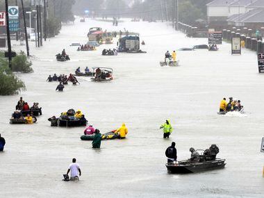 In this Aug. 28 photo, rescue boats fill a flooded street as flood victims are evacuated...