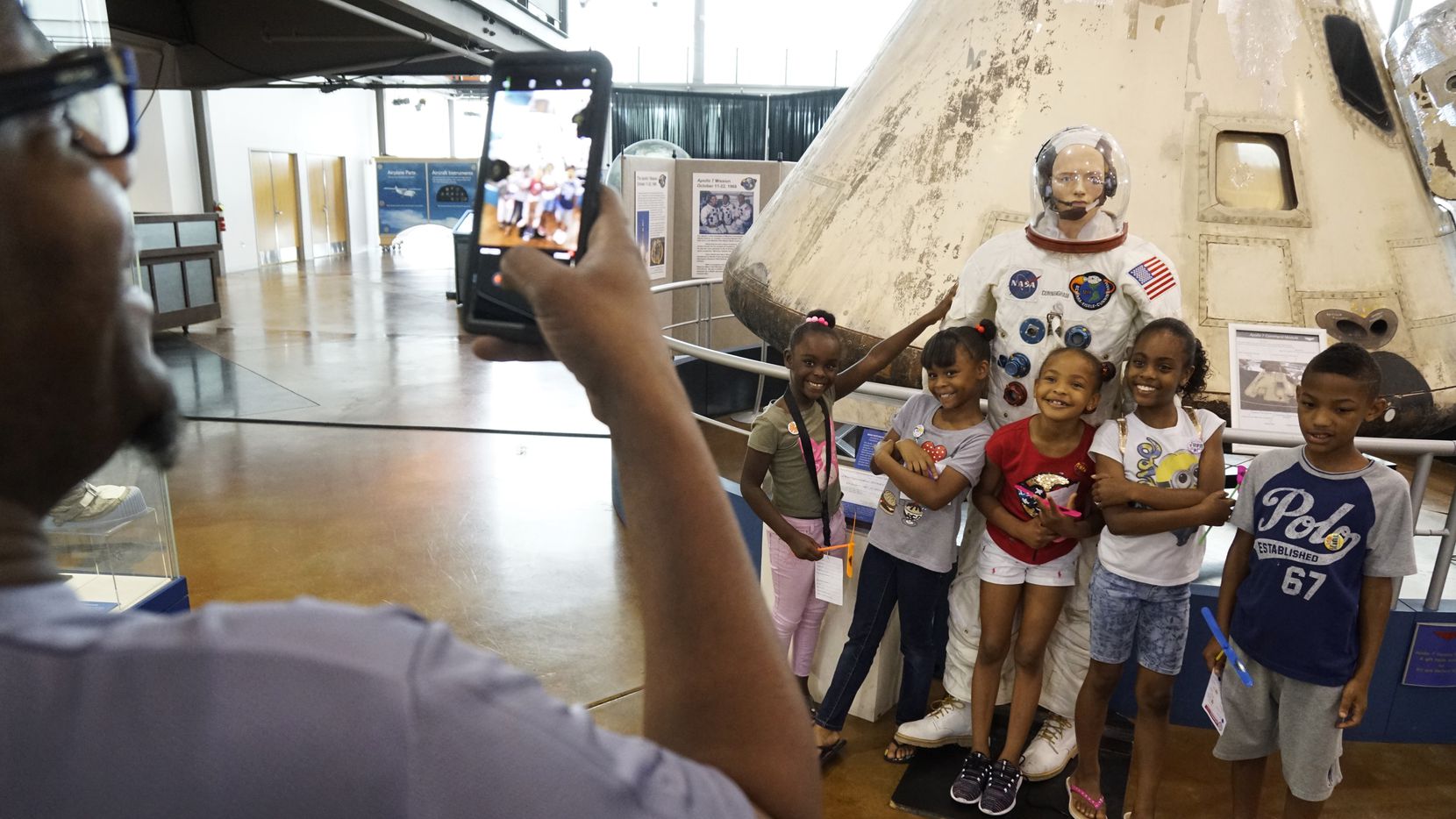 Tim Allen photographs Neriyah Aries (6), Amani Aries (8), Timia Allen (7), Leandra Chaires (11), and Devin Fitzgerald, in front of a space capsule at Big Thought's fifth annual Dallas City of Learning Turn Up at the Frontiers of Flight Museum in Dallas, Texas on Saturday, June 23, 2018.
