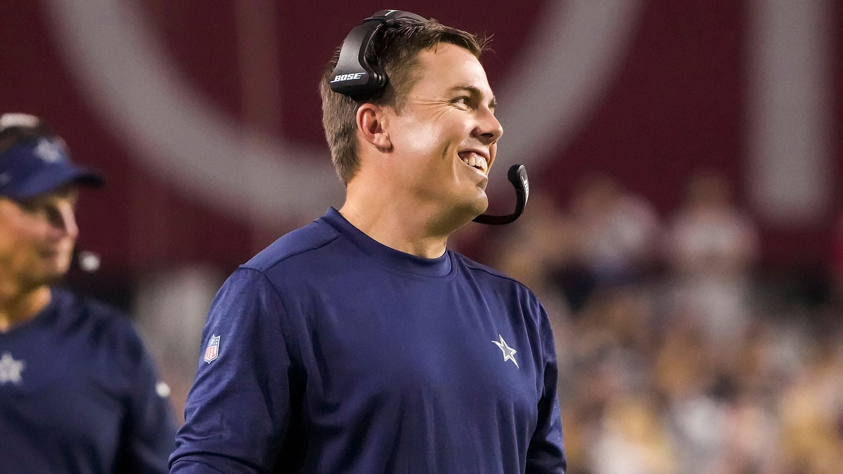 Dallas Cowboys offensive coordinator Kellen Moore smiles on the sidelines during the second half of a preseason NFL football game against the Arizona Cardinals at State Farm Stadium on Friday, Aug. 13, 2021, in Glendale, Ariz.
