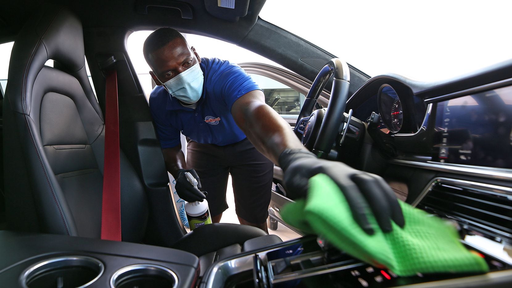 At Tommy Terrific's Car Wash in Plano, a worker cleans a vehicle while wearing a mask to...