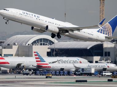 A United Airlines plane takes off above American Airlines planes on the tarmac at Los Angeles International Airport on Oct. 1.