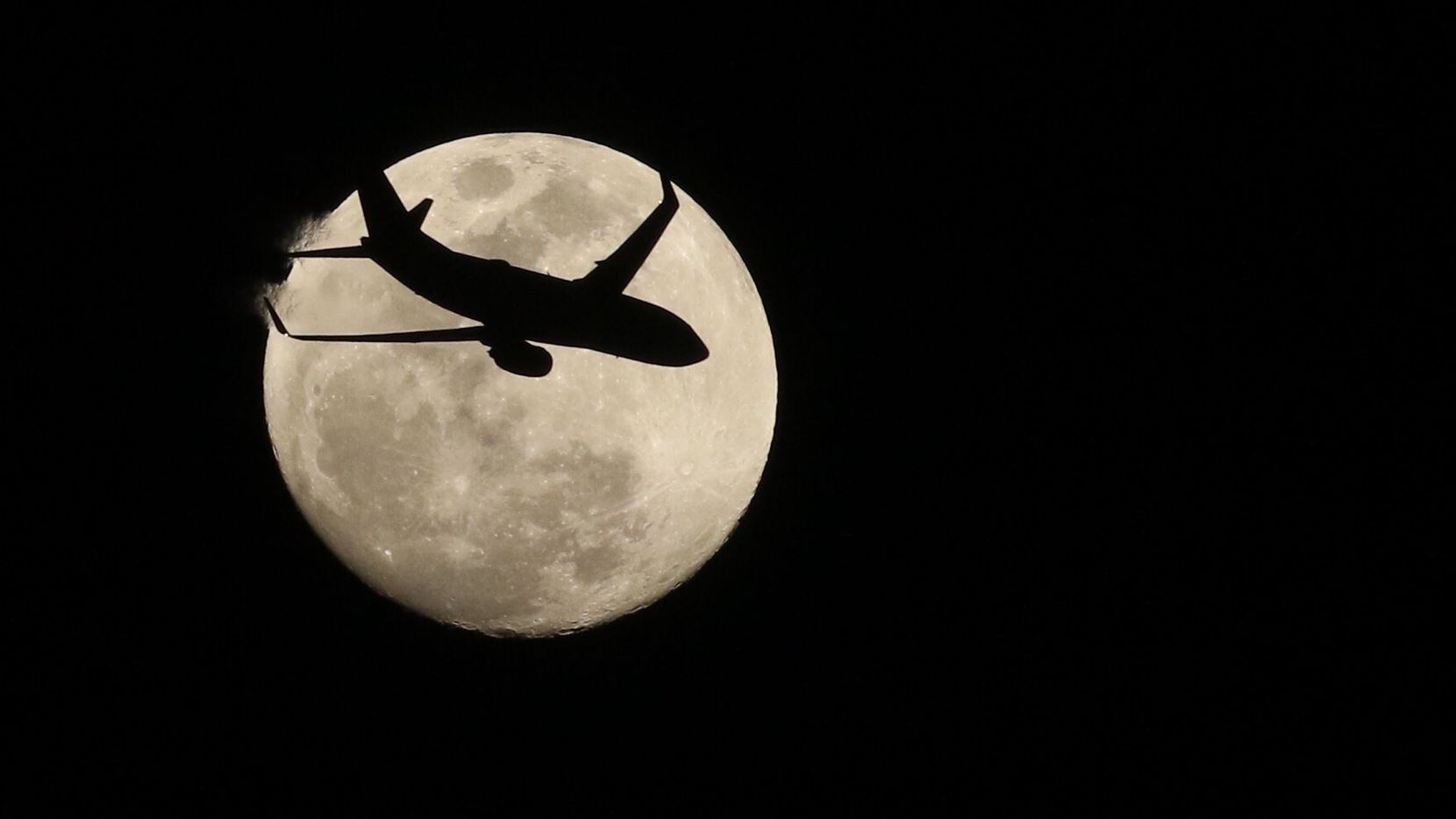 A Southwest jet is silhouetted against the moon after taking off from Love Field on Monday...