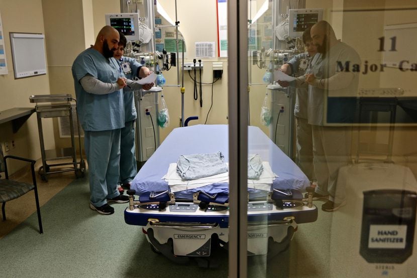 Un doctor y una enfermera atienden a un paciente de flu en una sala de emergencias en...