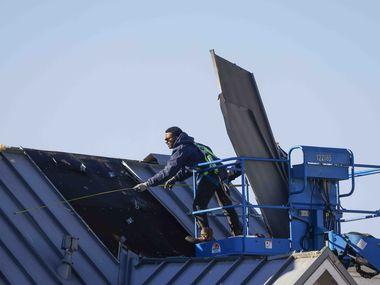 Crews work as they board up a damaged roof at Extra Space Storage in Grapevine on Wednesday,...