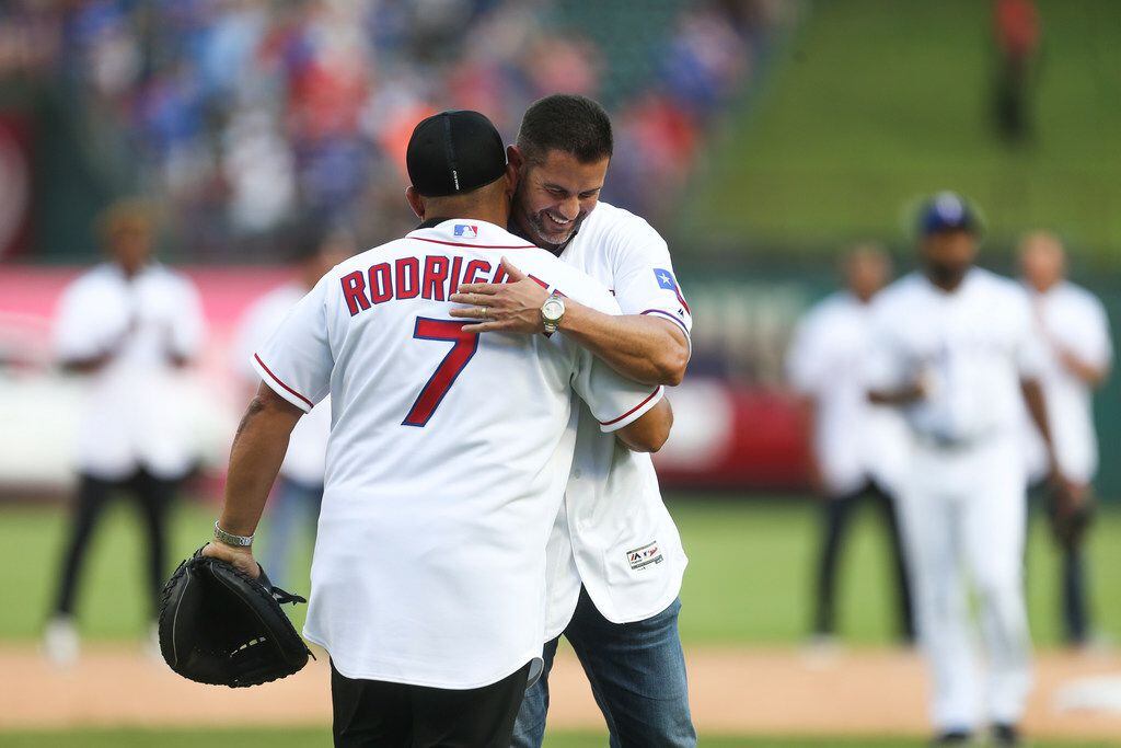 Former Texas Rangers catcher Ivan "Pudge" Rodriguez embraces former infielder Michael Young...