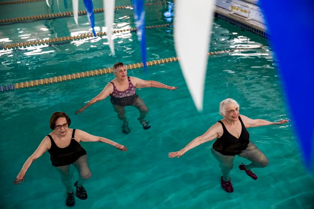 June Lieb, Nancy Weber and Miriam Cohen do single leg stands during swimming exercise class...