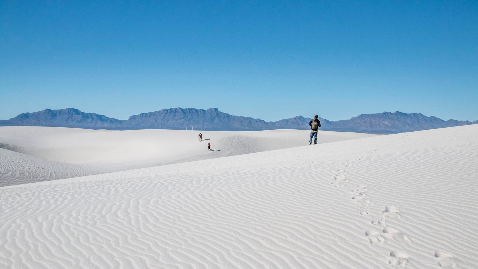 Hikers traverse White Sands National Park, which is home to a 176,000-acre gypsum dune...