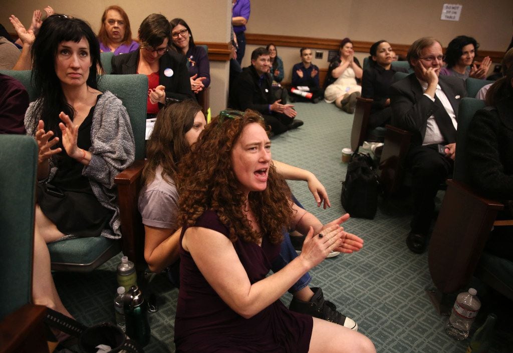 Erica Nix (front) applauds in the overflow room as members of the Senate State Affairs...