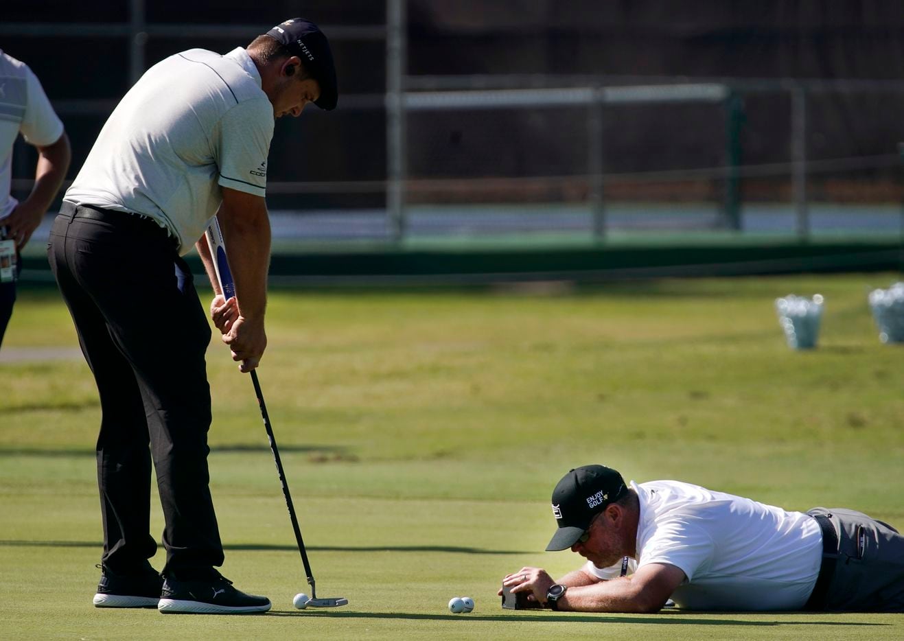 PGA Tour caddie Tim Tucker uses a smartphone to record golfer Bryson DeChambeau's putting as...