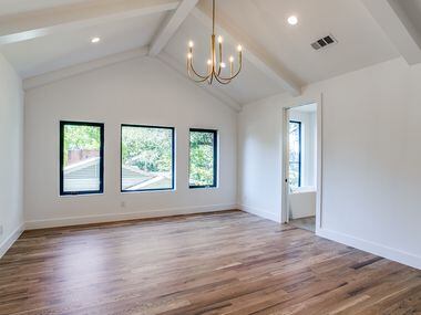 The master bedroom features light wood floors, vaulted ceilings and a brass chandelier.