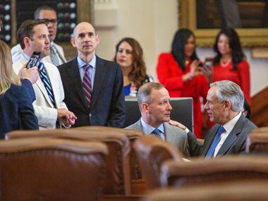 State Rep. Four Price (left) kneels and chats with Gov. Greg Abbott on the House floor just...
