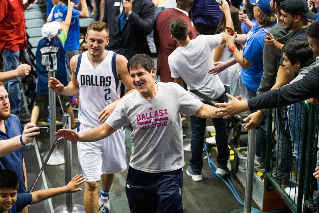 Dallas Mavericks owner Mark Cuban celebrates with fans as he leaves the court with guard...