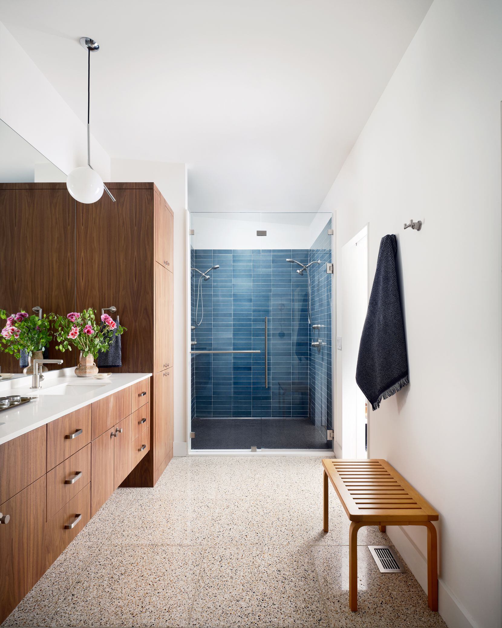 The shower in the primary features blue hand-glazed tiles, as well as Caesarstone...