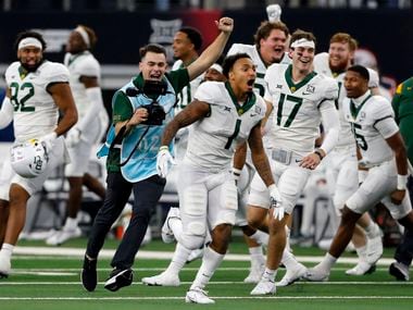 A school photographer (blue smock) celebrates with Baylor Bears running back Trestan Ebner (1) and the remainder of the Baylor bench at the end of  the Big 12 Championship football game against Oklahoma State at AT&T Stadium in Arlington on Saturday, December 4, 2021.
