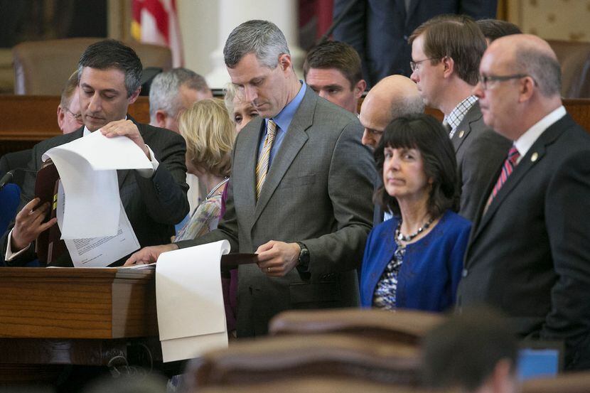 Southlake GOP Rep. Giovanni Capriglione, left, flips through pages of his bill as he answers...